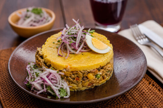  Causa peruana elaborada con capas de papa amarilla y pollo desmenuzado, coronada con huevo cocido y aceituna negra, servida como una especialidad cl&aacute;sica de la gastronom&iacute;a peruana.
