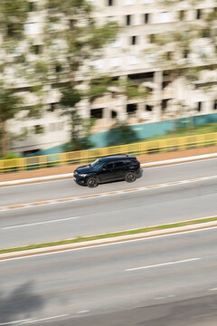Black Haval H6 side view cruising urban highway, Midsize Hybrid SUV travelling on city road