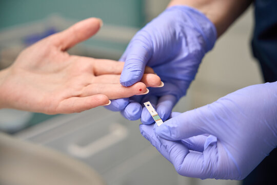 Medical professional performing finger prick test on patient indoors
