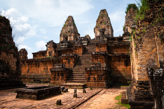 View of the ancient stone temple of Pre Rup with its tiered pyramid structure, intricate carvings, and weathered brick walls under a bright sky in Krong Siem Reap, Siem Reap Province, Cambodia.