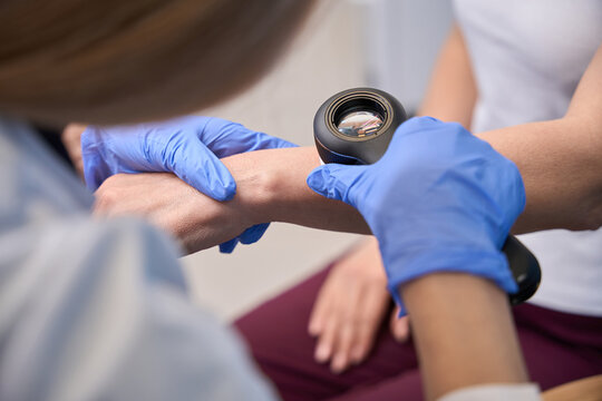 Two women examining skin in medical office with dermatoscope