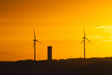 Obraz premium Wind turbines generating clean energy at sunset
