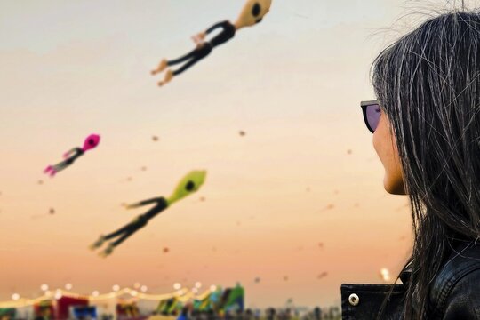 Doha, Qatar - 22nd january, 2026:woman spectator watch colorful giant kites flying above public park during Doha kite festival at sunset. Popular famous Cultural event Middle East lifestyle