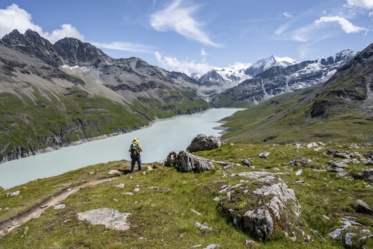 Mountaineer on a hiking trail at a blue mountain lake, reservoir Lac des Dix, behind mountain peak Mont Blanc de Cheilon, H&eacute;rm&eacute;nence, Valais Alps, Valais, Switzerland