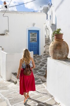 White and blue Cycladic houses, Young woman with red dress in the old town of Lefkes, Paros, Cyclades, Greece