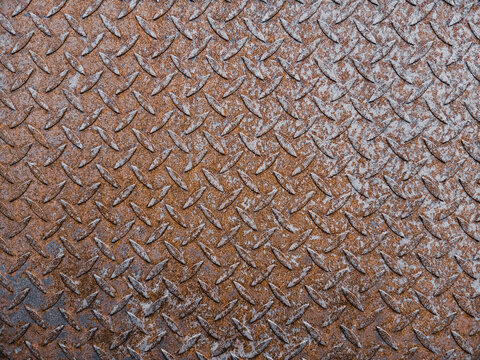 Rusty diamond plate metal filling the entire frame area in a full close up perspective showing detailed industrial texture for heavy engineering background or construction wallpaper advertising.