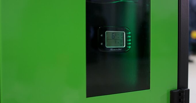 Close up view of a black heavy duty metal door hinge attached to a green storage machine