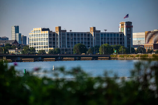 View of the historic industrial building with its clock tower and American flag overlooking the river in Everett, Massachusetts, United States.