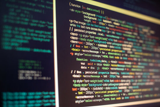 Close-up of colorful code on a computer screen in a dimly lit room.