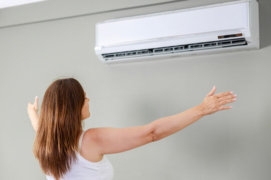 Woman enjoying cool air from air conditioner