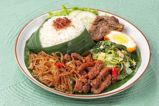 Nasi Berkat Wonogiri, a classic Indonesian ceremonial meal from Wonogiri, Central Java, featuring steamed rice with assorted side dishes such as fried chicken or beef, tempeh, vegetables, sambal, nood
