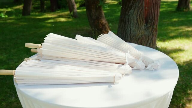 Stylish white vintage umbrellas provide shade from the hot, bright sun on a sunny summer day. Wedding ceremony for the bride and groom.