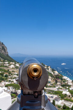 Coin telescope overlooking coastal town and sea in Capri, Italy