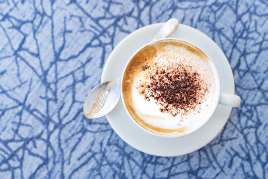 Cappuccino coffee with cocoa dusting on patterned table, Italy
