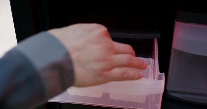Worker opening a secure automated locker cabinet door to pull out a black drawer component