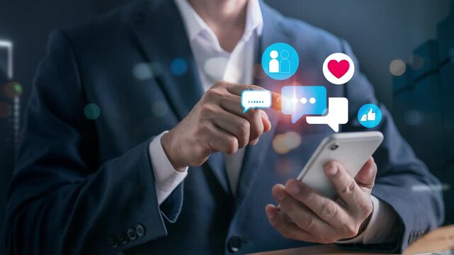 Close-up of a businessman using a smartphone to interact with colorful social media icons like chat bubbles, hearts, likes, and follower profiles for marketing engagement and digital communication.