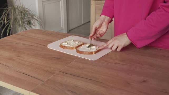 Spread mayonnaise on bread with a spoon to make sandwiches. Making sandwiches at home.