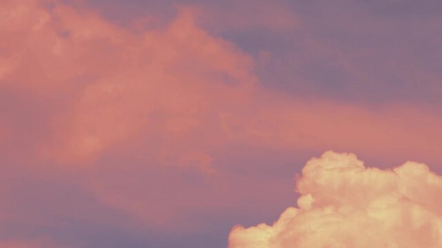 Time Lapse footage of dreamy surreal pinkish fluffy clouds flowing on light blue sky