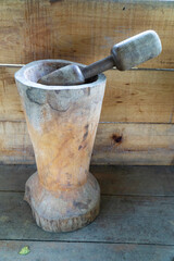 Naklejka premium Traditional rustic wooden mortar and pestle pilon carved by hand on a vintage wood background for grinding grains.
