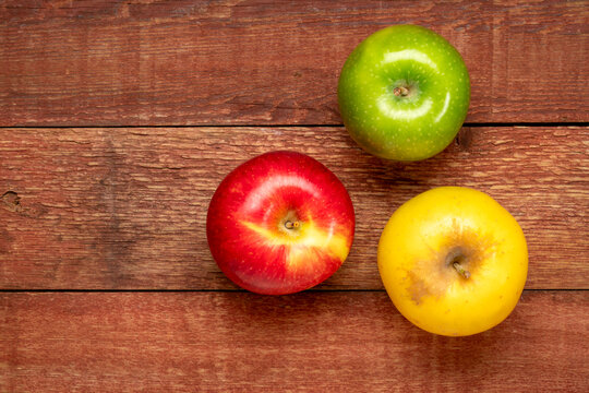 red, green and gold apples on weathered rustic barn wood table