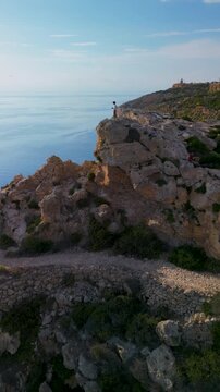 Man silhouette standing on mountain cliff rock horizontal sea aerial drone view.
