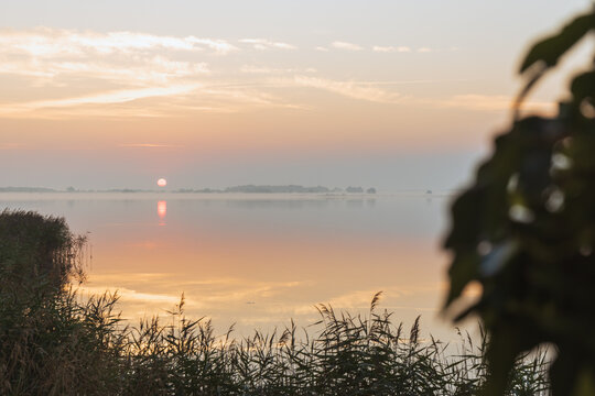 Sonnenaufgang mit spiegelnden Wolken und Nebel &uuml;ber der Ostsee