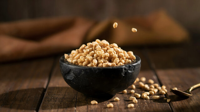 Bowl filled with toasted crispy puffed rice grains on a rustic wooden table