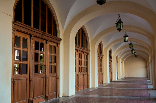 Elegant arched corridor with vintage hanging lanterns. Historic building facade with light and shadows