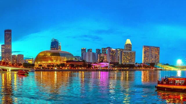 Panorama of marina bay skyline with evening lights reflecting in the sea at blue hour. Singapore cityscape by night. Night scene waterfront.