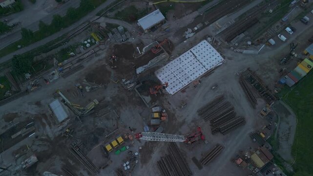 high altitude drone footage overlooking cranes excavators and construction foundations surrounded by natural landscape