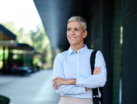 Portrait of a young businesswoman woman walking down the street, surrounded by moder corporate office buildings