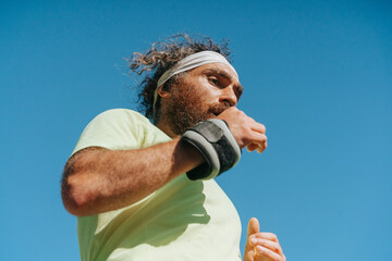 Obraz premium Athletic bearded man running with wrist weights outdoors