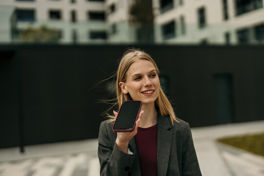 Businesswoman recording audio message on smartphone outdoor