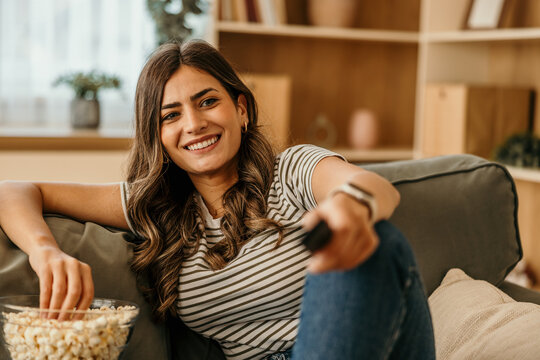 Woman relaxing on sofa watching tv eating popcorn