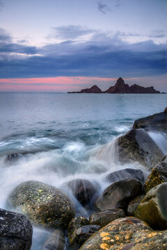 Beautiful sunset at Saturraran beach in the Basque Country Spain with long exposure silky sea waves on golden sand and dramatic rocks under cloudy sky