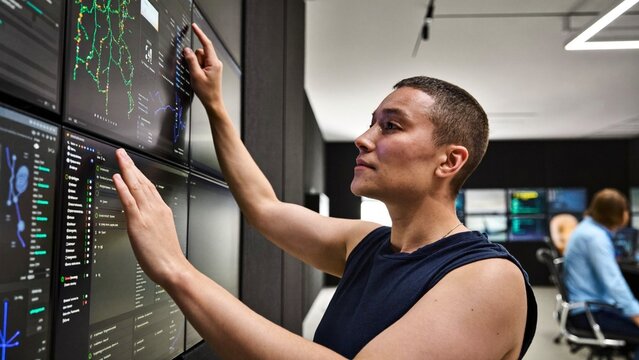 A Cybersecurity Analyst Monitoring Threat Dashboards on a Wall of Screens in a Dark Security Operations Center, in a Futuristic Tech Lab. Photorealistic Candid Editorial Stock Photograph