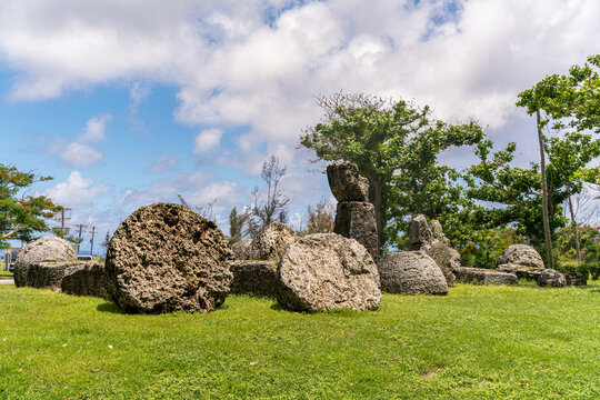 View of the House of Taga, an ancient Chamorro archaeological site with massive latte stone pillars set in a grassy field under a blue sky in San Jose, Tinian, Northern Mariana Islands.