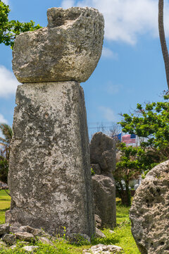 View of the ancient House of Taga latte stone monolith standing in a grassy field under a bright blue sky in San Jose, Tinian, Northern Mariana Islands.