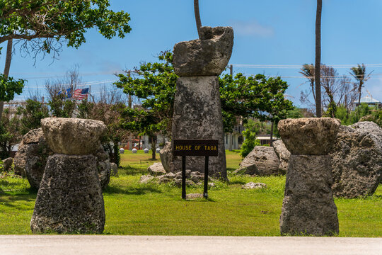 View of the ancient latte stone pillars at the House of Taga archaeological site, surrounded by green grass and palm trees in San Jose, Tinian, Northern Mariana Islands.