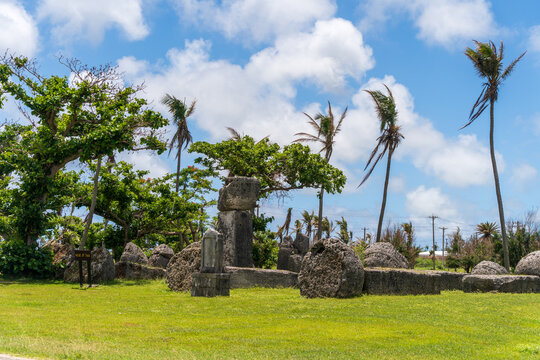 View of the ancient House of Taga megalithic site with weathered latte stones set in a grassy field under a bright blue sky in San Jose, Tinian, Northern Mariana Islands.