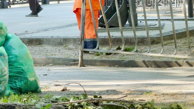 A diligent worker cleans the sunny city sidewalk in Simferopol, Crimea. Their hard work brings a peaceful sense of order and satisfaction to the bright urban environment.