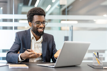 Professional man wearing a suit and glasses. Smiling while engaging in a video call on a laptop....