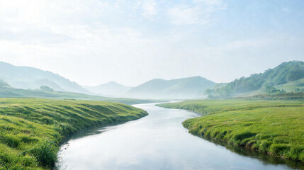 Fototapeta premium Serene landscape with a winding river through lush green hills and misty mountains under blue sky