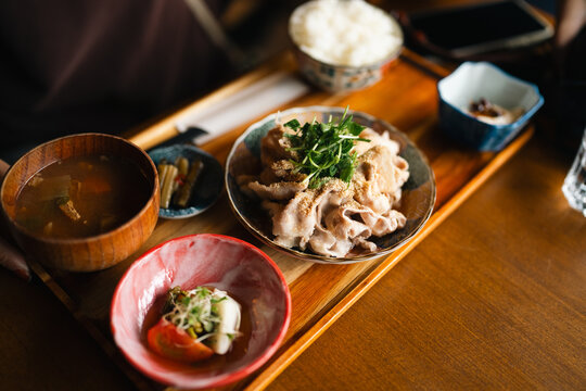 Japanese meal pork rice soup tofu tray wooden table ceramic bowl chopstick garnish served in warm natural light with traditional home style dining setting