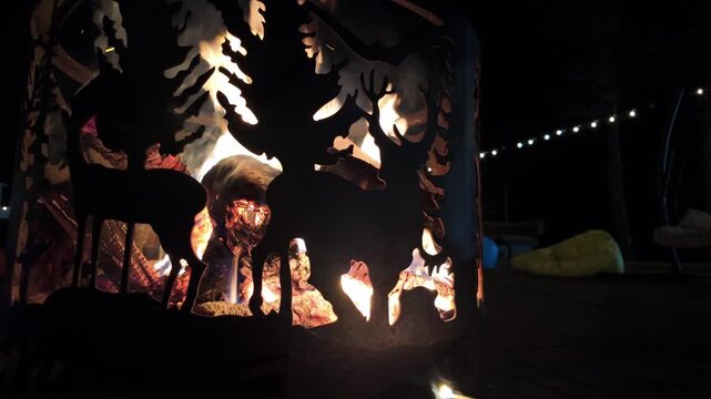 Fire Pit with Decorative Wildlife Cutouts and Person Tending the Flames at Night