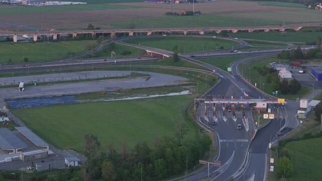 A1 motorway toll plaza featuring transport infrastructure, vehicle circulation and strategic logistics connections across the Po Valley, telephoto aerial shot.
