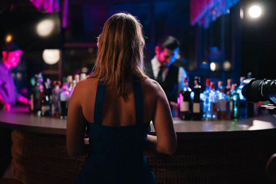 Bar nightclub woman bartender bottle counter cocktail nightlife neon back view woman nightclub bar counter with bartender, bottle display, cocktail service, colorful neon light, relaxed social