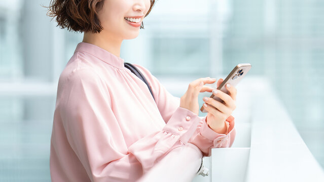 オフィス街でスマートフォンを使う女性・ビジネスウーマン, Businesswoman Using a Smartphone in an Office District