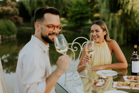 Couple enjoys dinner at lake with wine and food during warm evening light