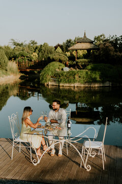 Couple enjoys meal by the water at a garden in late afternoon light